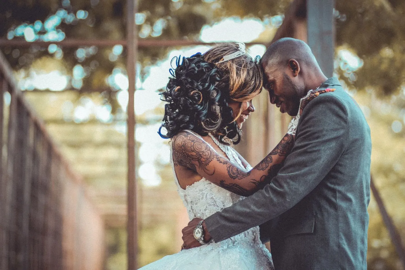 A bride and groom embracing forehead to forehead outdoors
