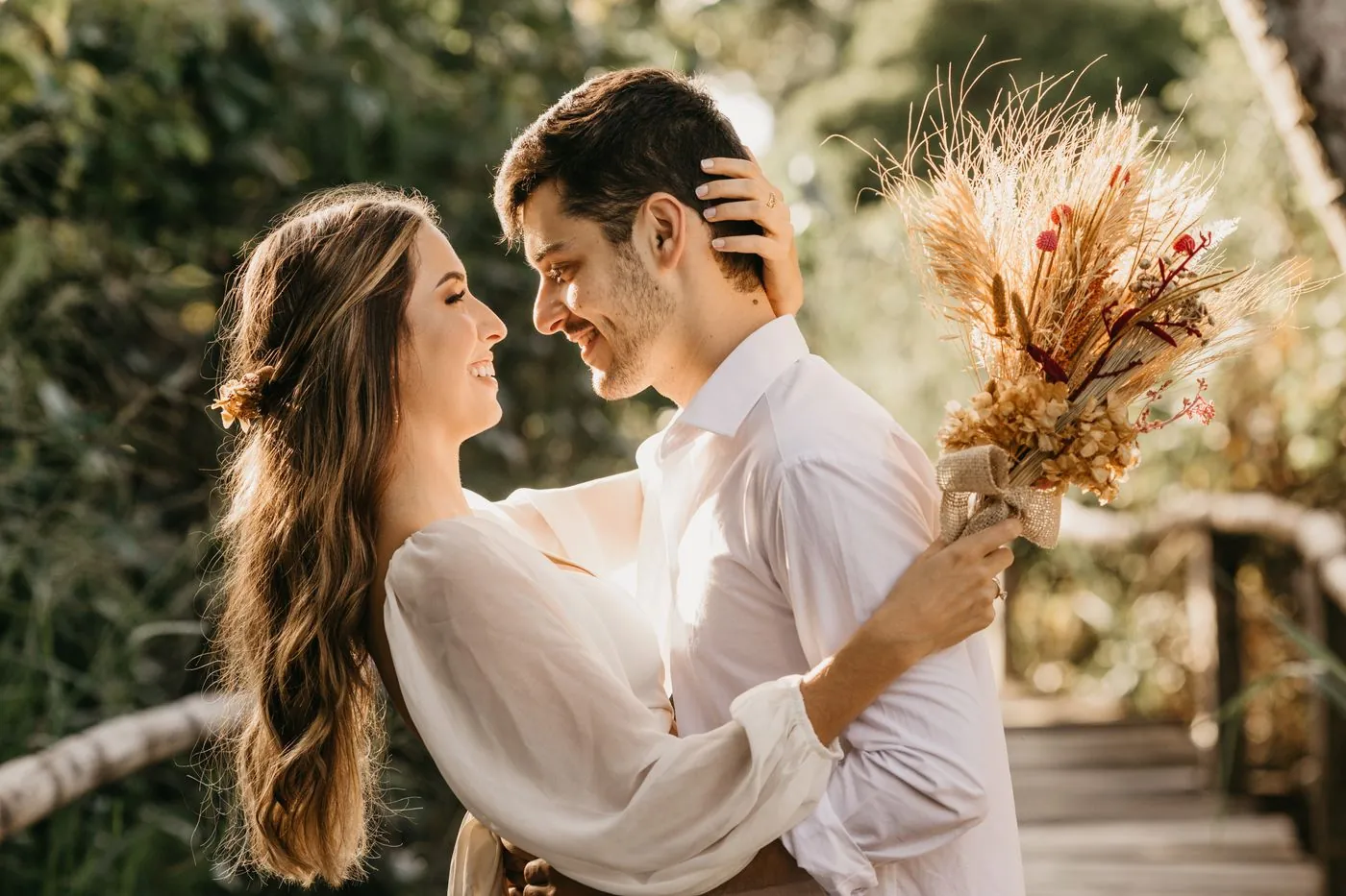 An engaged couple smiling at each other outdoors at golden hour