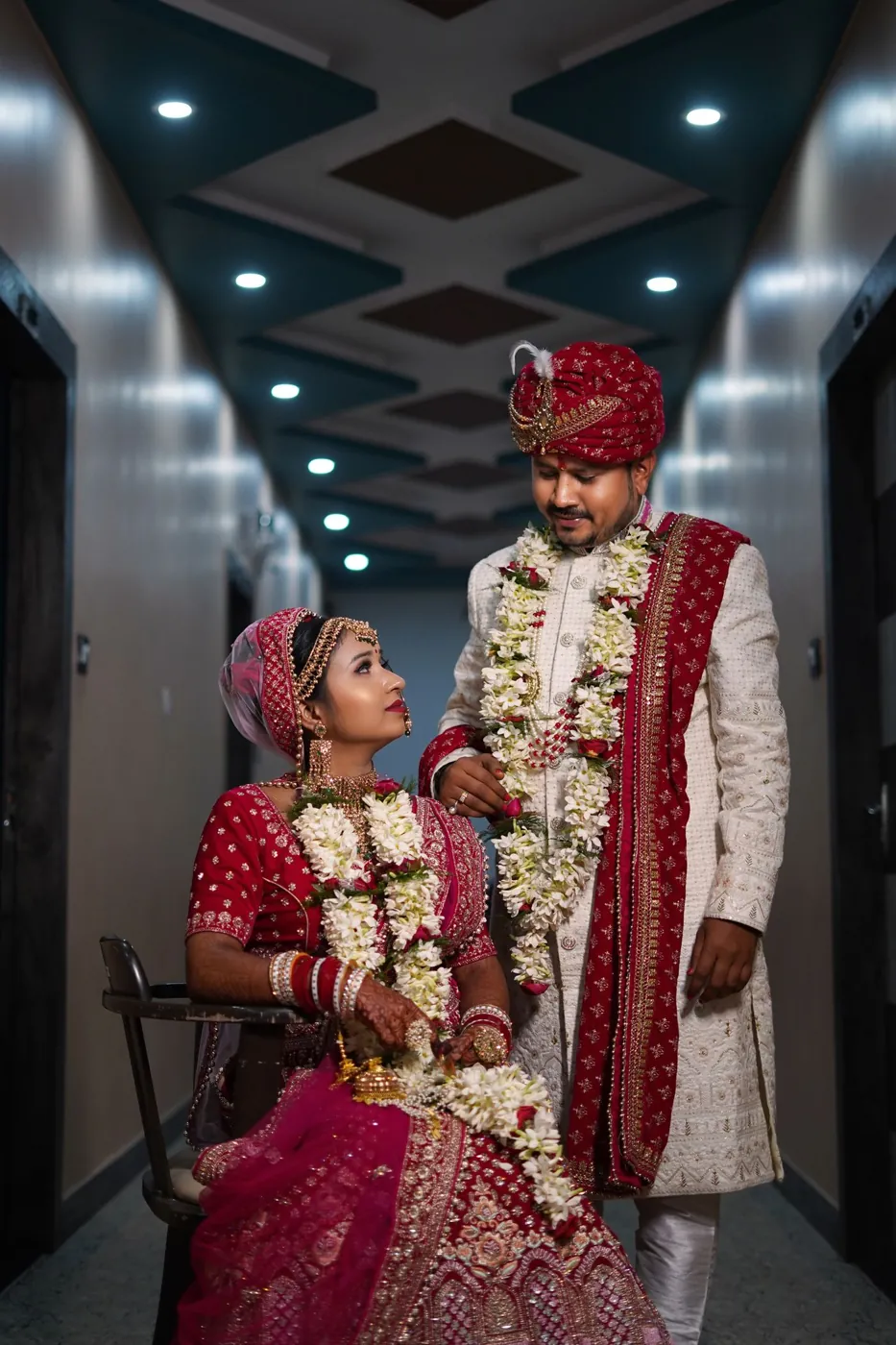 An Indian bride and groom in traditional attire wearing flower garlands