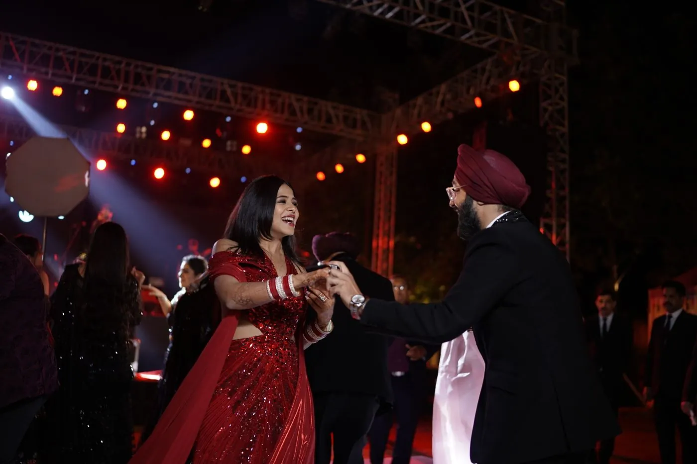 Wedding guests in formal and traditional attire dancing at an evening reception